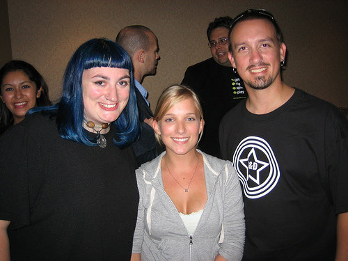 Ellen standing between Dawn, who has blue hair and wears a black top, and Drew, who wears a black t-shirt, at what appears to be an early podcasting event.